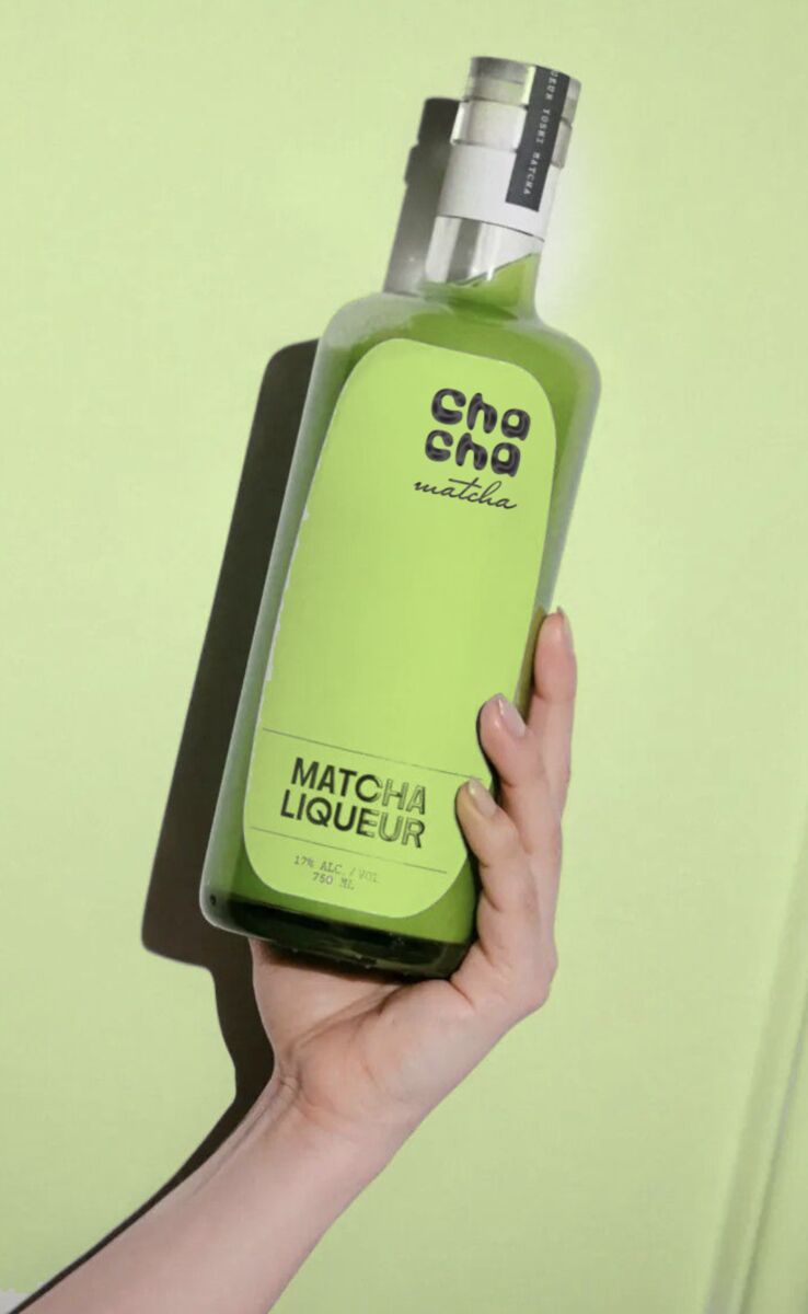 Bottle of Chacha matcha liqueur held against pale green